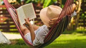 Photo of person reading a book in a hammock