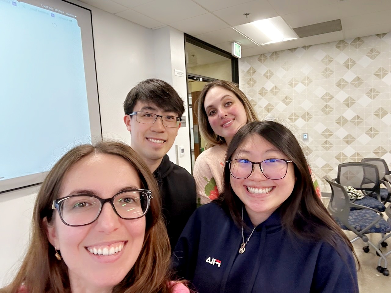 Photo of a group of four optometry students in a classroom smiling.