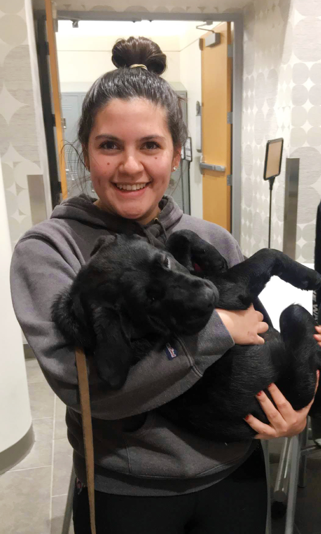 Melanie Vela holding black labrador puppy