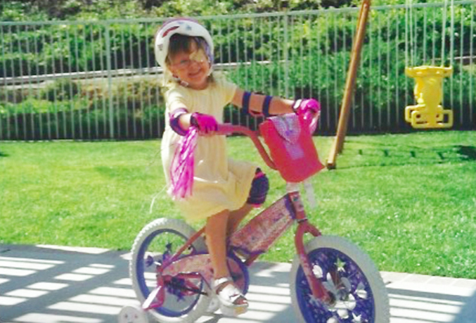 Elementary-aged McKenna, riding on a bicycle